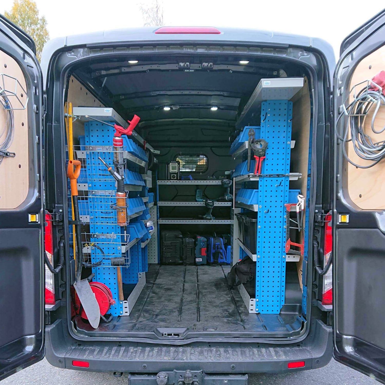 Sahkorepo Oy:n huolto- ja asennuspakettiauto takaovet avoinna ja sisalla nakyy sahkoasennustoihin tarvittavia tyokaluja ja varusteita.